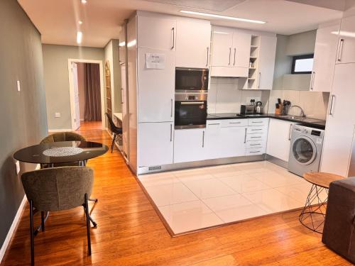 Una cocina con gabinetes blancos y una mesa y sillas. en Lofty-Space, en Gaborone