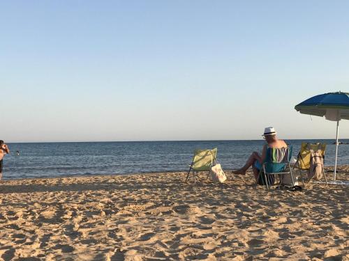 a man sitting in lawn chairs on the beach at Accommodates 5 people between Ibla and Ragusa in Ragusa