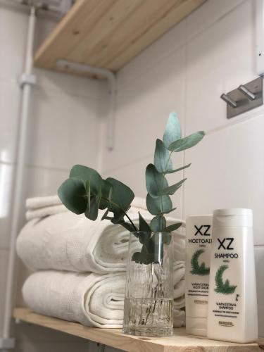 a vase with a plant on a table next to towels at Elf apartment in Rovaniemi