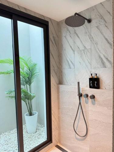 a bathroom with a shower with a potted plant at About P พูลวิลล่า ชะอำ in Ban Phu Wai