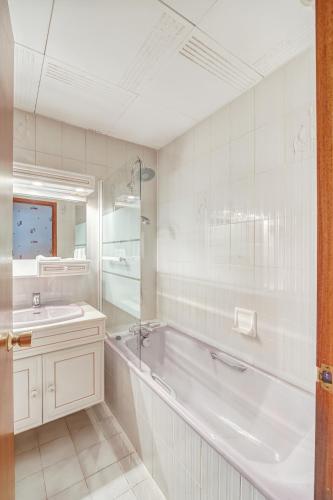 ein weißes Badezimmer mit Badewanne und Waschbecken in der Unterkunft Contact Hôtel Des Deux Moulins Limoges, Proche de la gare in Limoges