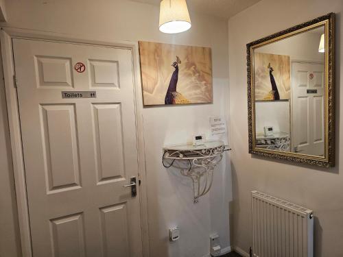 a bathroom with a white door and a mirror at Rosag Guest House Rainham in Rainham