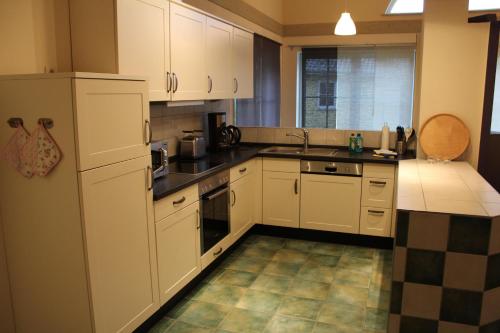 a kitchen with white cabinets and a tile floor at Reitcamp Börgerende GmbH & Co. KG in Börgerende-Rethwisch