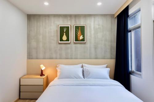 a bedroom with a bed and two paintings on the wall at City Pause Hostel in Sathani Bang Su
