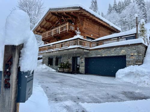 una casa con un garaje en la nieve en Chalet Casa Di Più - Vue Panoramique & Spa - À 2 Pas du Centre Des Gets !, en Les Gets