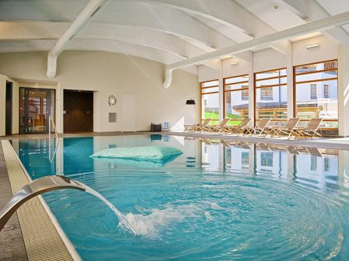 a swimming pool with chairs in a building at Schweizerhof Ferienwohnungen Lenzerheide Haus 5 in Lenzerheide