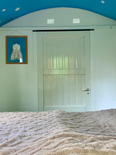 a white door in a room with a bed at Kleine Pipowagen op natuurcamping in Wedde