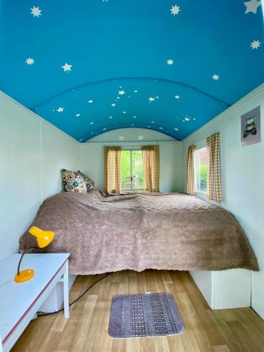 a bedroom with a bed with a blue ceiling at Kleine Pipowagen op natuurcamping in Wedde
