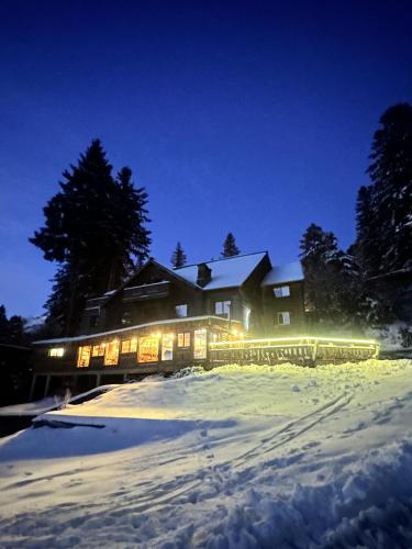 a house with lights in the snow at night at LE BUFADOU - Gîte Auberge - in Laveissière