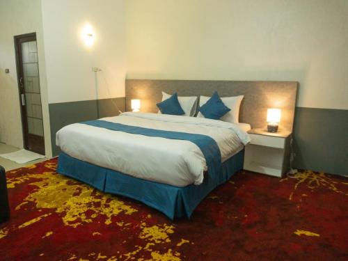 una camera da letto con un letto grande con cuscini blu e bianchi di Grand Aulia Hotel Padang Panjang a Padangpanjang