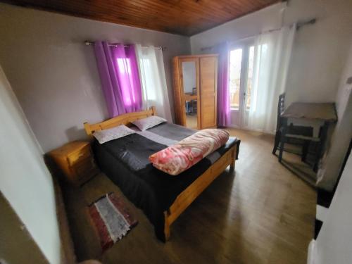 een slaapkamer met een bed in een kamer met paarse gordijnen bij Chez Lalie in Mandriankeniheny