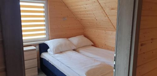 a small bed in a wooden room with a window at Nautica in Gąski