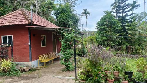 a red house with a yellow bench in a garden at Manna Homestay coorg in Kushālnagar