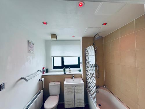 a bathroom with a toilet and a tub and a sink at WindyS Smart Home, you will love it in Basildon