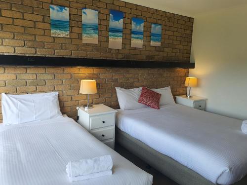 two beds sitting next to a brick wall at Bellbrae Motel in Torquay