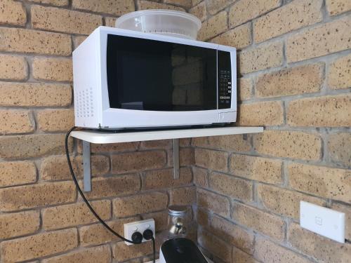 a microwave on a shelf on a brick wall at Bellbrae Motel in Torquay