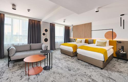 a hotel room with two beds and a couch at voco Katowice by IHG in Katowice