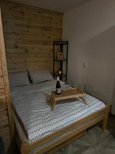 モクラ・ゴラにあるApartman Gorska priča, Mokra Goraのベッド1台(木製ヘッドボード、ワイン1本付)
