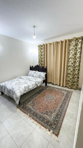 a bedroom with a bed and a rug and curtains at Comfort meets convenience 3BR by Airport & SGR in Nairobi