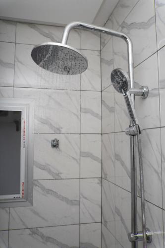 a shower with a shower head in a bathroom at Martha House New BELL Douala in Douala