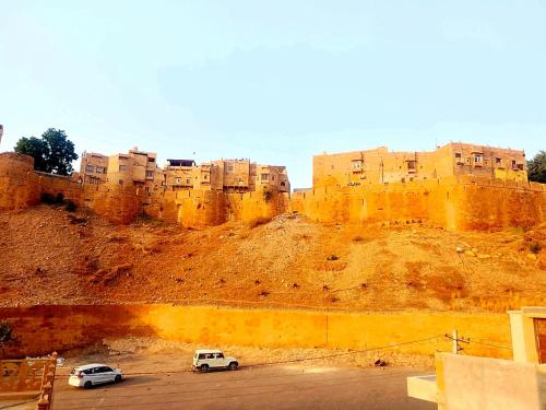 two cars parked in a parking lot in front of a castle at Hostel sakura Jaisalmer in Jaisalmer