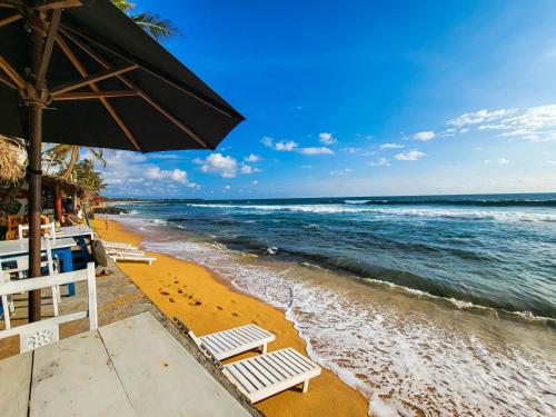 ein Strand mit Stühlen und einem Sonnenschirm und das Meer in der Unterkunft Beach Cabana By why not hikkaduwa in Hikkaduwa