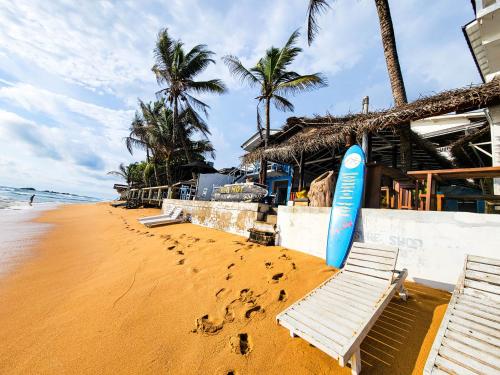 ein Strand mit zwei Bänken und einem Surfbrett darauf in der Unterkunft Beach Cabana By why not hikkaduwa in Hikkaduwa