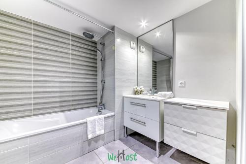 a white bathroom with a tub and a sink and a bath tub at Vinatier - Lyon 2 - LB - Large family apartment with parking in Lyon in Bron