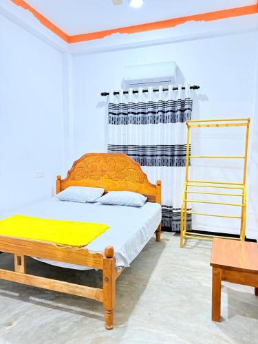 a bedroom with a wooden bed with a yellow blanket at J Rest in in Trincomalee