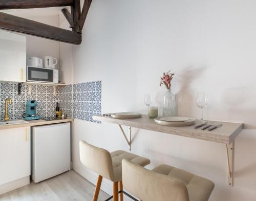 une cuisine avec une table, des chaises et un comptoir dans l'établissement Le Douillet, à Reims