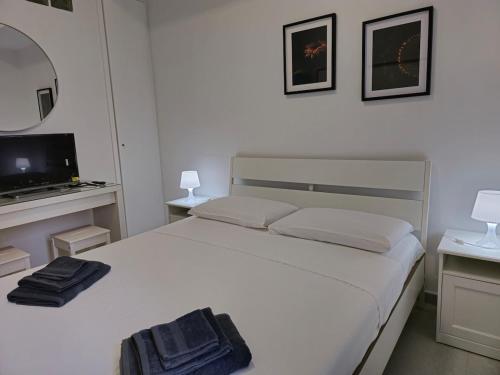 a bedroom with a white bed and a television at Casa Quarzo, bright and a stone's throw from the beach in Gaeta