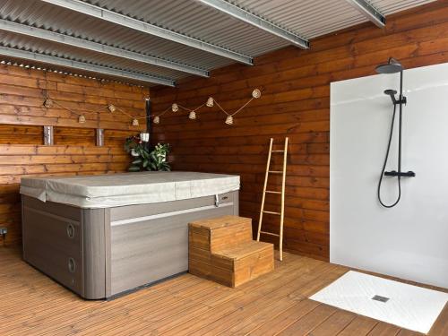 bañera de hidromasaje en una habitación con pared de madera en ORKY-MEL, en Petite Île