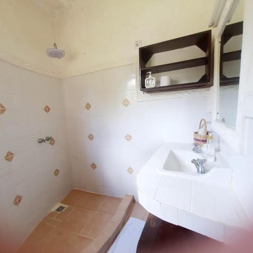 Un baño blanco con lavabo y espejo. en C House, en Malindi