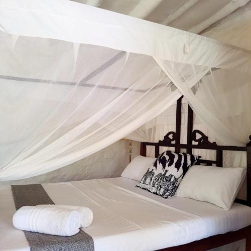 una cama con dosel y dos almohadas encima en C House, en Malindi