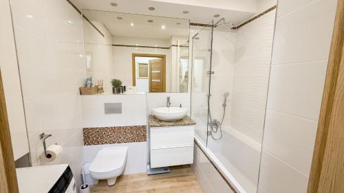 a white bathroom with a sink and a shower at Apartament Ptasia Góra in Kłodzko