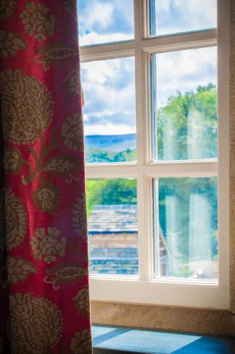 a window with a red curtain and a view at The Fleece Inn in Shireshead