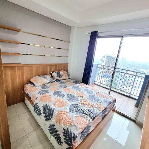 a bedroom with a bed and a large window at Apartemen Springwood by tuliproom in Pakulonan Dua