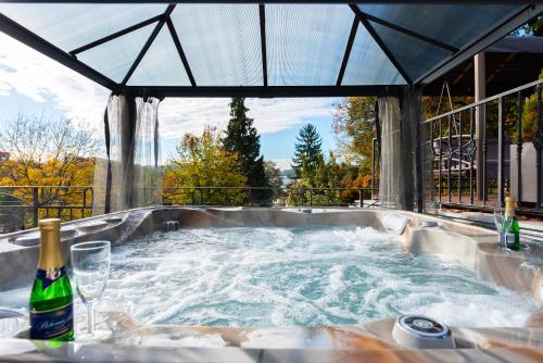 a jacuzzi tub with a bottle of champagne in it at Wellness & SPA boutique Hotel pod lipkami Prague in Prague