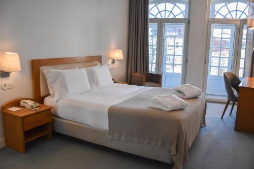 a hotel room with a bed with two towels on it at Hotel Toural in Guimarães