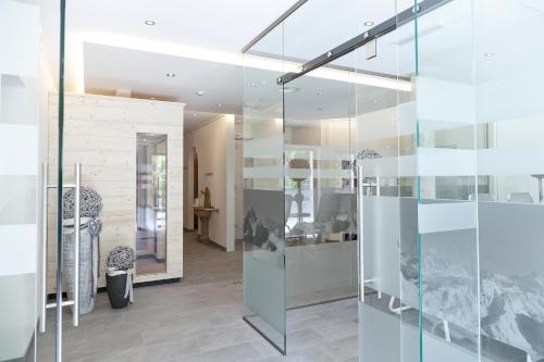 a glass wall in a living room with a table at Hotel Garni Rifflsee in Sankt Leonhard im Pitztal