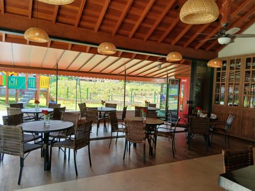 a dining room with tables and chairs and windows at Pequena Suíça Hotel Boutique in Chácara