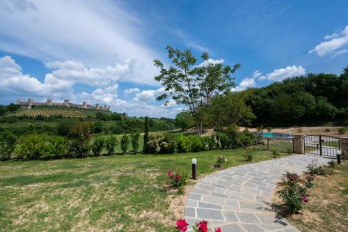 un giardino con un sentiero in pietra e un castello sullo sfondo di Borgo Campassini, Monteriggioni a Monteriggioni