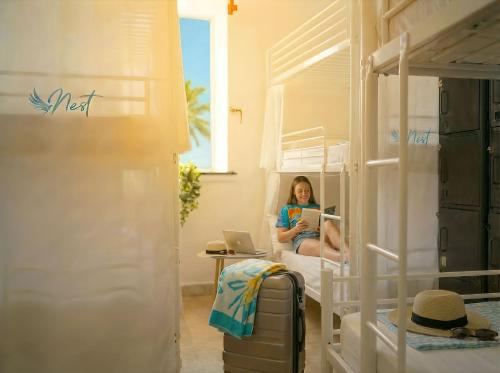 a woman sitting in a bunk bed reading a book at Hostel Las Palmas by Youroom in Las Palmas de Gran Canaria