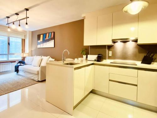 a kitchen with white cabinets and a living room with a couch at Orzan Beach Surf Apartment in A Coruña
