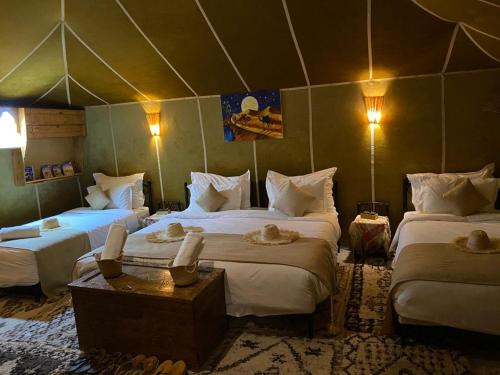a room with three beds in a tent at DesertGlow camp in Merzouga
