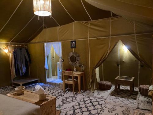 a room with a tent with a bed and a table at DesertGlow camp in Merzouga