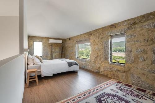 a bedroom with a bed and a stone wall at Romantic Lemon Grove Cottage with Private Pool - Oporto Lemon Farm, near Porto in Valpedre