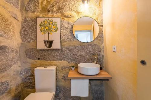 a bathroom with a sink and a toilet and a mirror at Romantic Lemon Grove Cottage with Private Pool - Oporto Lemon Farm, near Porto in Valpedre