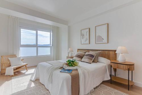 a white bedroom with a large bed and a window at Blue Ocean Deluxe in Sanxenxo