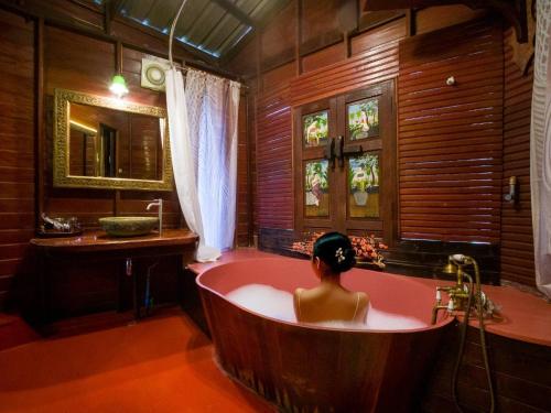una mujer sentada en una bañera en un baño en Kaengkrachan Boathouse Paradise Resort, en Kaeng Kachan